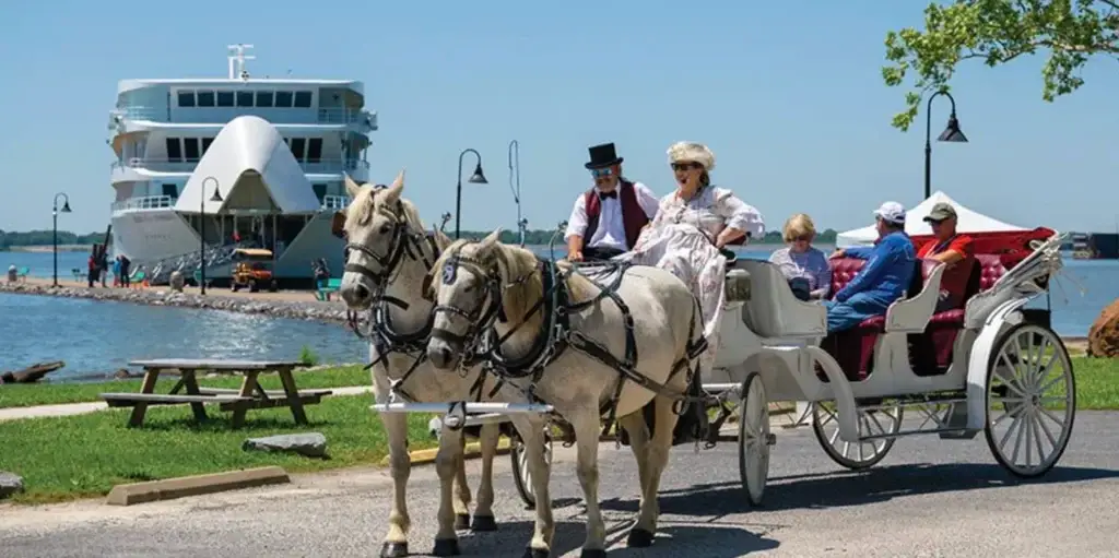 Photo of a horse drawn carriage excursion carrying passengers near a docked river cruise ship