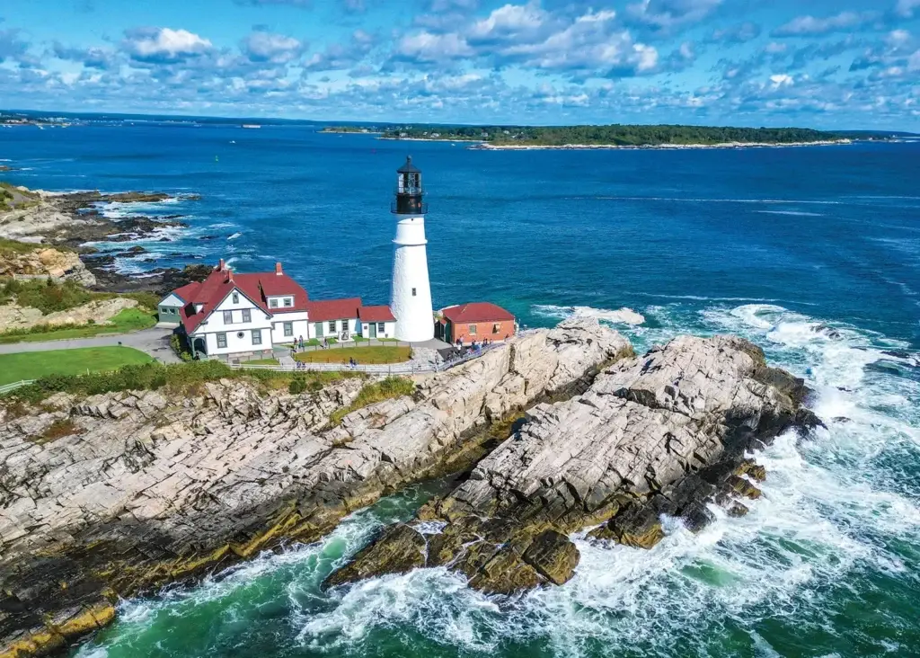 Photo of Portland Head Light standing on rocky Atlantic coastline under sunny skies