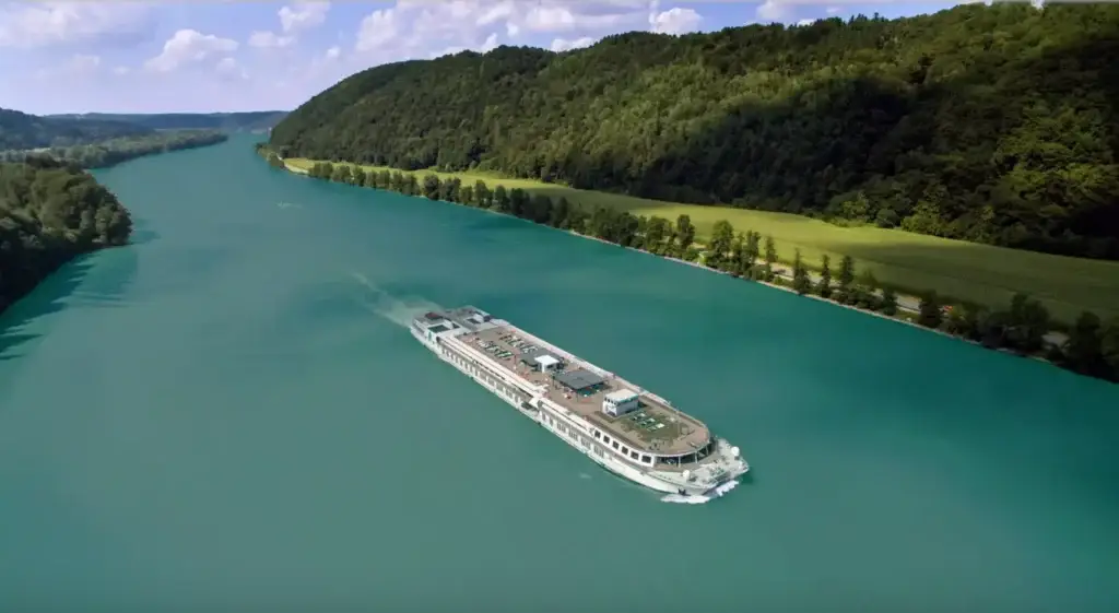 Photo-of-aerial-view-of-river-cruise-vessel-navigating-scenic-green-valley-waters