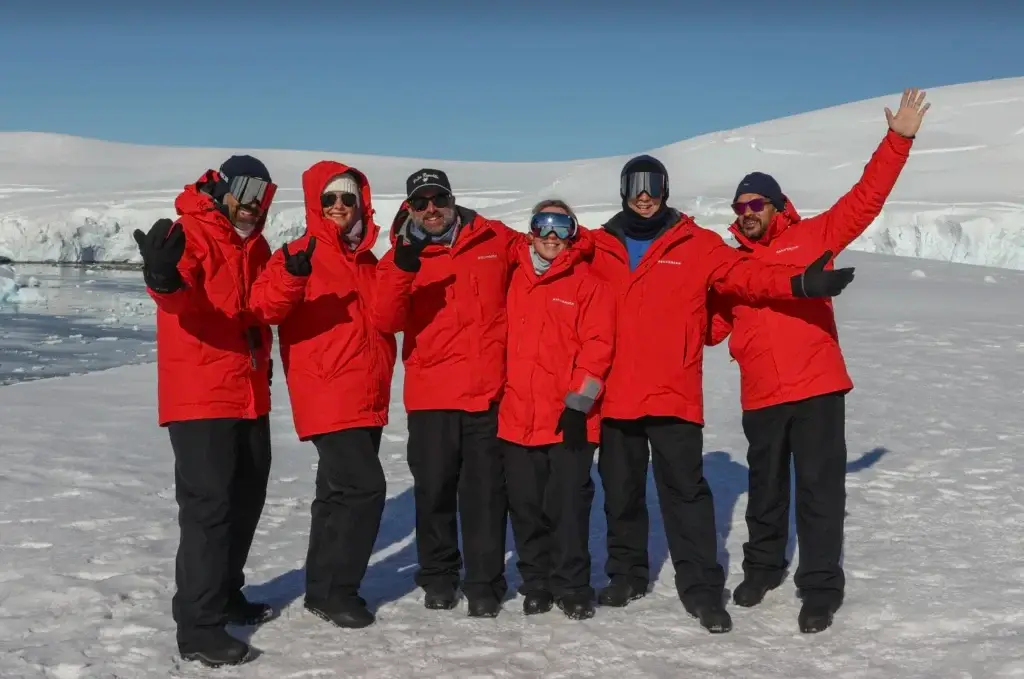 Photo of a group of expedition guests posing on snow in red Silversea parkas