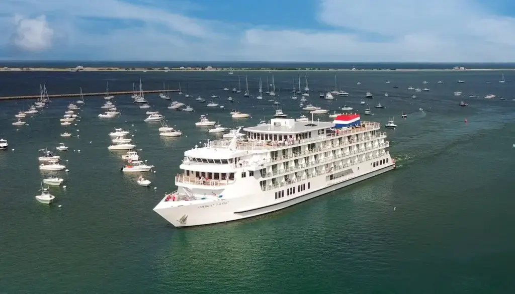 Photo of aerial view showing American Patriot ship navigating near a harbor filled with sailboats