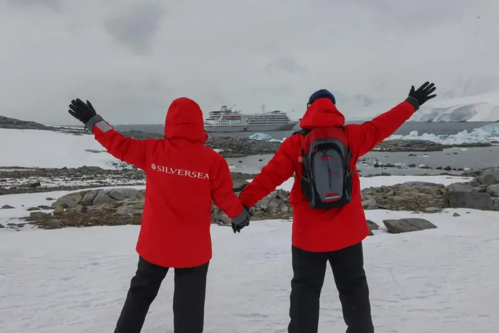 Photo of passengers waving at Silversea expedition ship Silver Cloud anchored in Antarctica