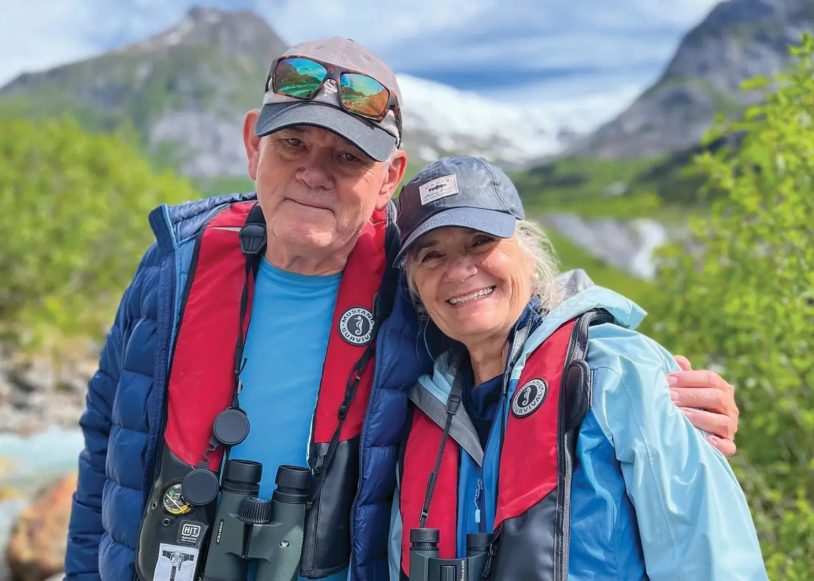 photo smiling couple wearing warm gear and binoculars outdoors in Alaska
