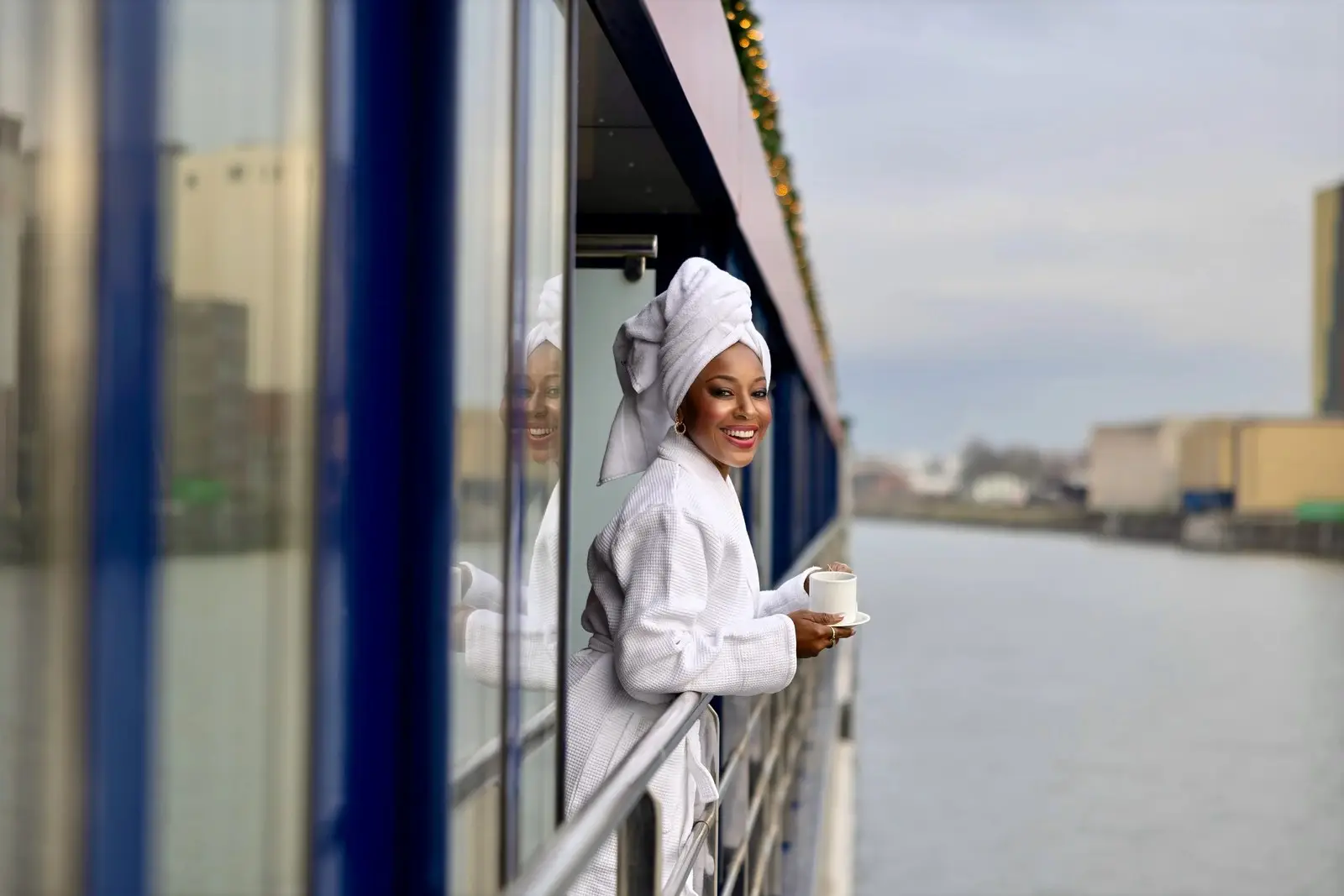 Photo of AmaWaterways cruise guest in a bathrobe and hair towel on a balcony holding a cup